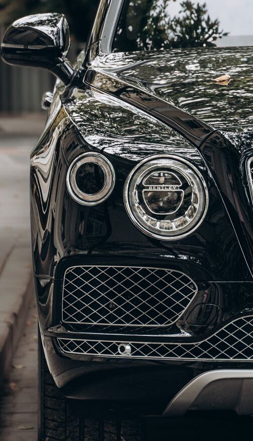 Close-up of a black luxury car showcasing its sleek, reflective surface and elegant design.