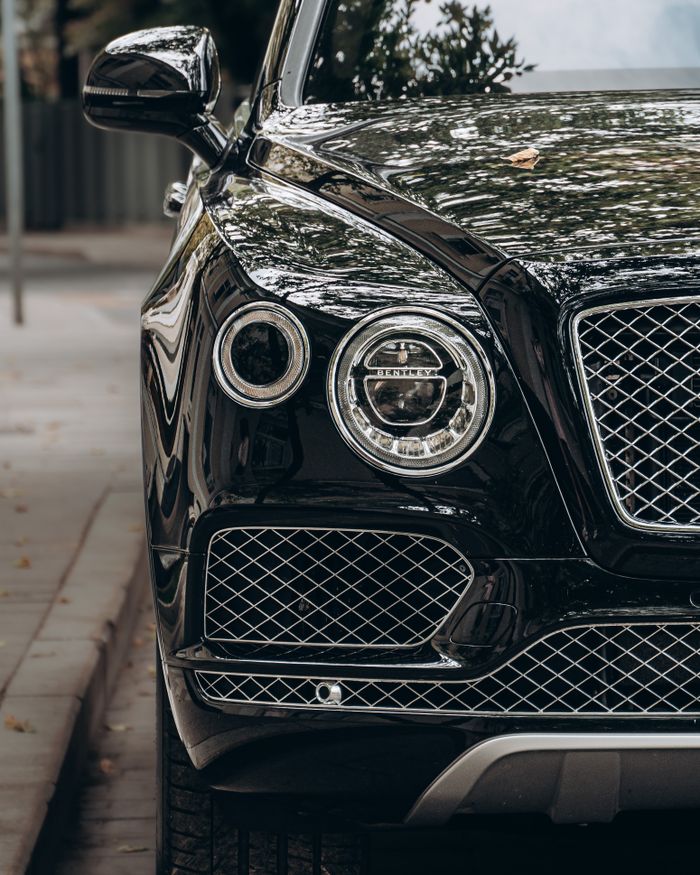 Close-up of a black luxury car showcasing its sleek, reflective surface and elegant design.